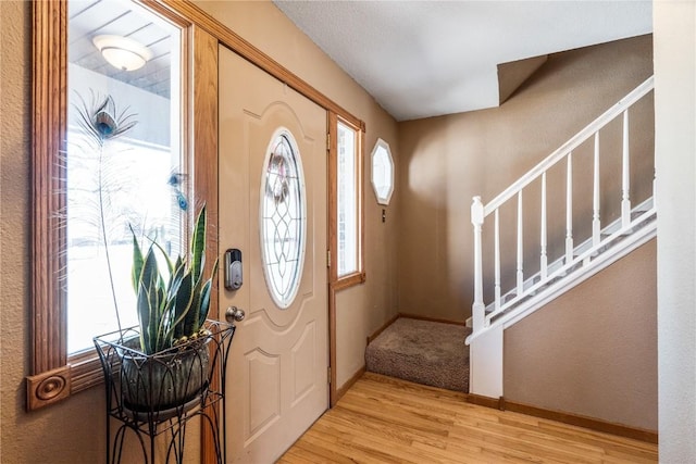 foyer with stairs, baseboards, and wood finished floors