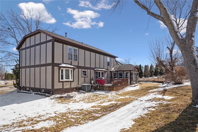 view of snowy exterior with board and batten siding, central AC, and a wooden deck