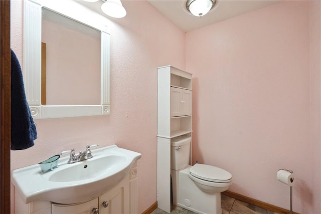 bathroom featuring toilet, tile patterned floors, baseboards, and vanity