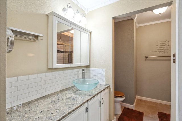 bathroom with toilet, vanity, baseboards, decorative backsplash, and crown molding