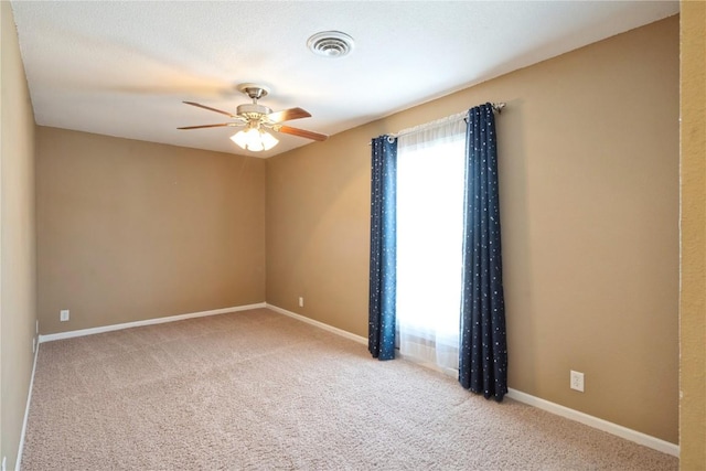 carpeted spare room featuring baseboards, visible vents, and a ceiling fan