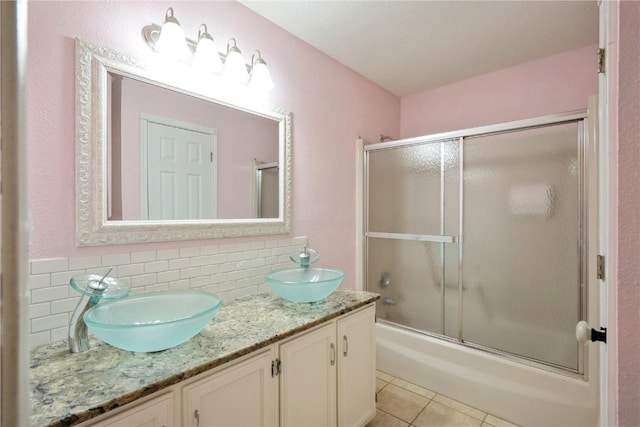 bathroom with shower / bath combination with glass door, tasteful backsplash, a sink, and tile patterned floors