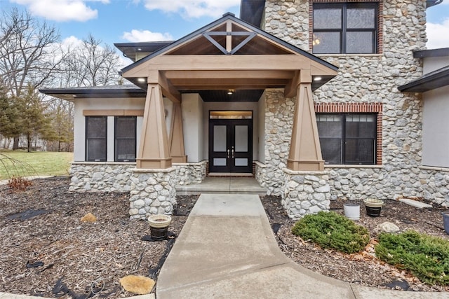 doorway to property with french doors, stone siding, and stucco siding