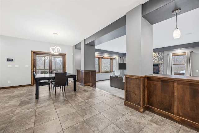 dining space with baseboards, an inviting chandelier, light tile patterned flooring, and a fireplace