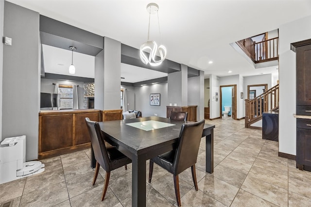 dining space featuring light tile patterned floors, baseboards, and stairs