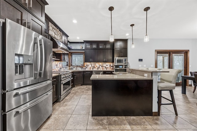 kitchen with backsplash, a breakfast bar area, range hood, stainless steel appliances, and a sink