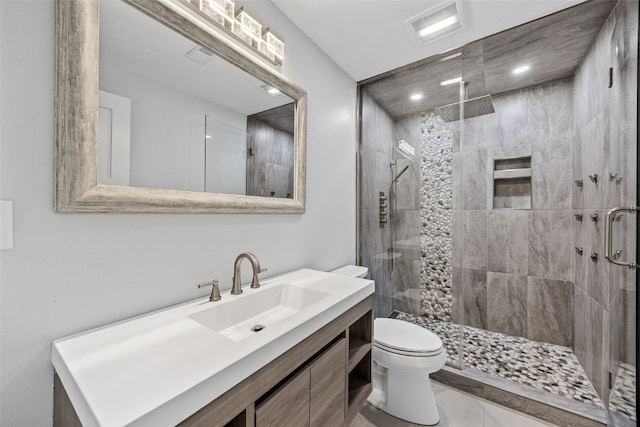 bathroom featuring vanity, toilet, visible vents, and a stall shower