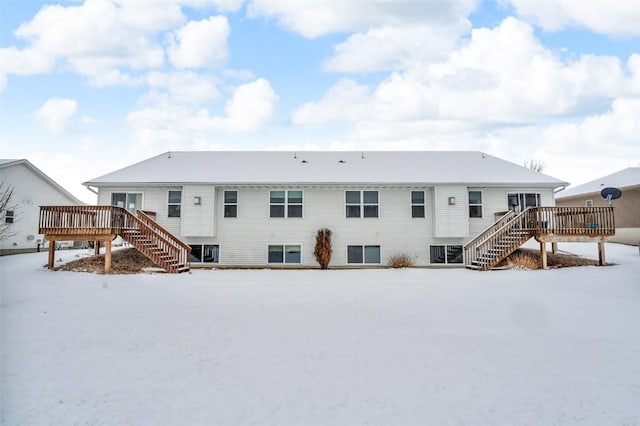 snow covered house with a wooden deck and stairs