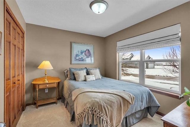 bedroom featuring light colored carpet, a closet, and baseboards