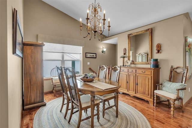 dining room with baseboards, an inviting chandelier, vaulted ceiling, and light wood finished floors