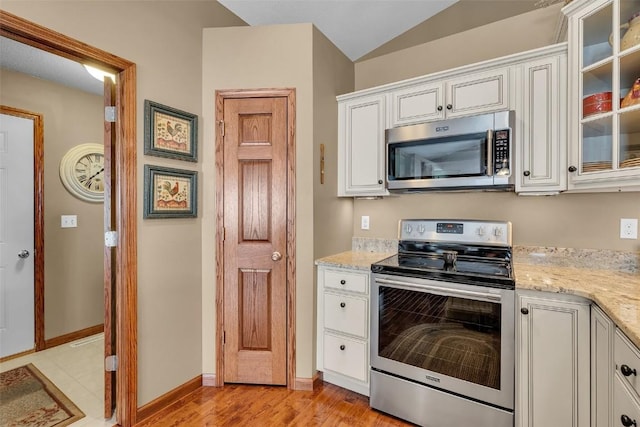 kitchen with stainless steel appliances, light stone countertops, glass insert cabinets, and white cabinets