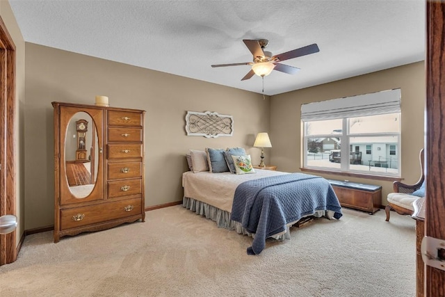 bedroom featuring light colored carpet, a textured ceiling, baseboards, and ceiling fan