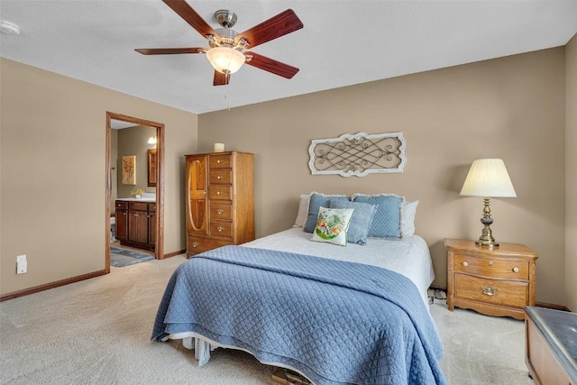 bedroom featuring light carpet, a ceiling fan, ensuite bathroom, and baseboards