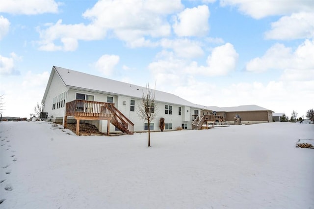 snow covered rear of property featuring a wooden deck and stairs