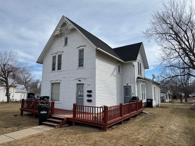 rear view of house featuring a lawn and a wooden deck