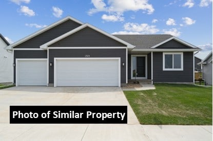 ranch-style house featuring a garage, concrete driveway, and a front lawn