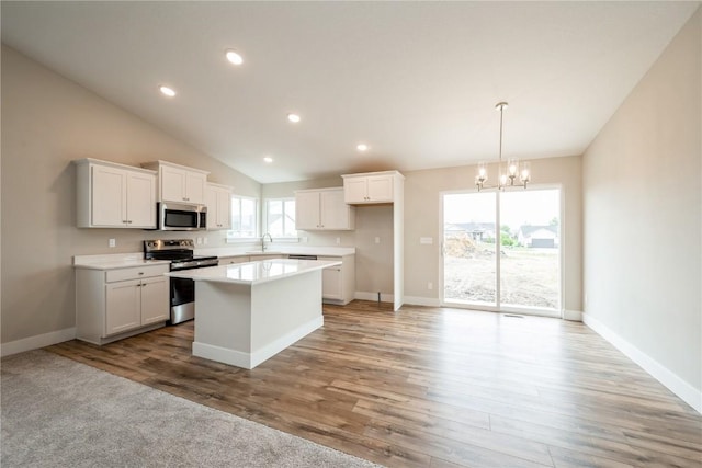6166 Cope Dr, Marion, IA 52302 - kitchen with stainless steel appliances, a sink, a chandelier, a center island, and white cabinetry