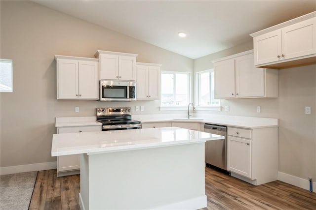 6166 Cope Dr, Marion, IA 52302 - kitchen with appliances with stainless steel finishes, a sink, vaulted ceiling, white cabinetry, and wood finished floors