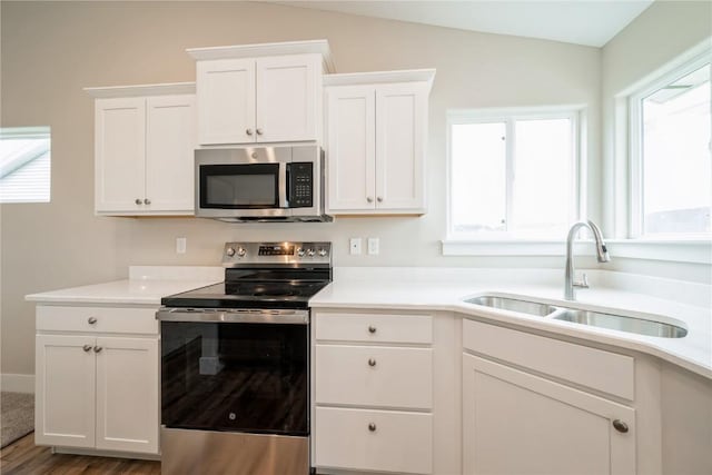 6166 Cope Dr, Marion, IA 52302 - kitchen featuring appliances with stainless steel finishes, a sink, white cabinetry, lofted ceiling, and light countertops