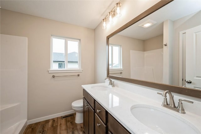 6166 Cope Dr, Marion, IA 52302 - bathroom featuring baseboards, wood finished floors, toilet, a shower, and double vanity