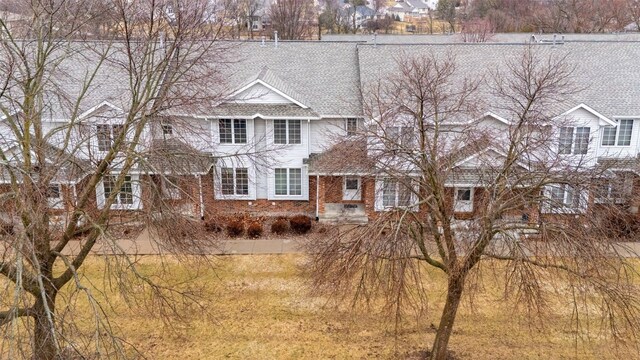 view of front facade with brick siding and roof with shingles