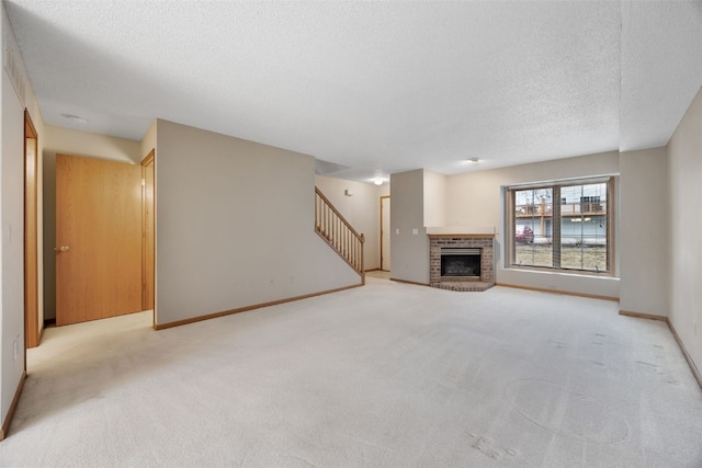 unfurnished living room featuring light colored carpet, a fireplace, a textured ceiling, and stairs