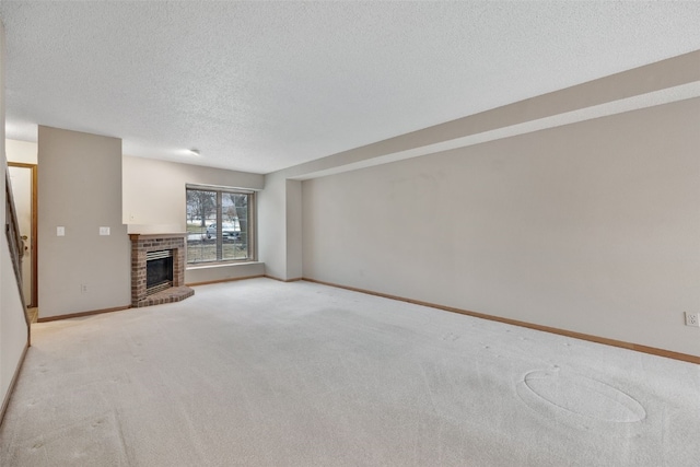 unfurnished living room with light colored carpet, a brick fireplace, a textured ceiling, and baseboards