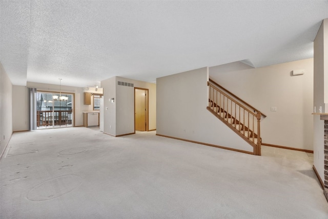 unfurnished living room featuring stairway, baseboards, visible vents, a textured ceiling, and a notable chandelier