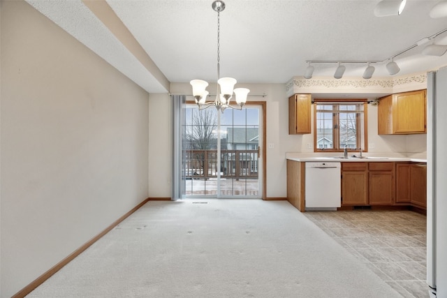 kitchen with light countertops, baseboards, white dishwasher, and a sink