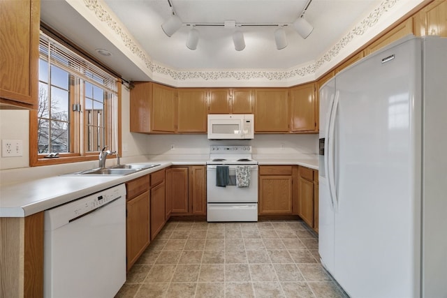 kitchen with brown cabinetry, white appliances, and a sink