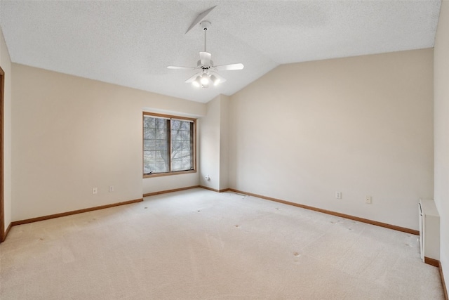 carpeted spare room with a textured ceiling, a ceiling fan, baseboards, and vaulted ceiling