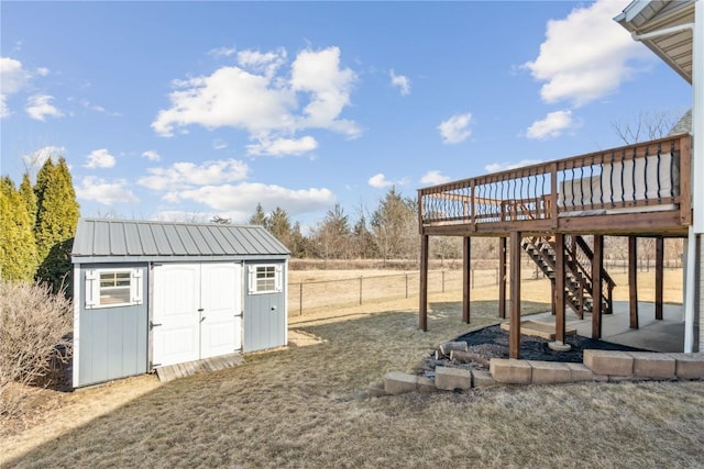 view of yard with a storage unit, a deck, fence, an outdoor structure, and stairs