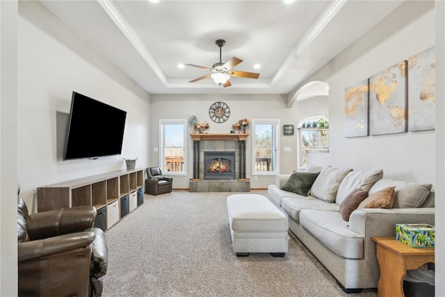 living area with a raised ceiling, crown molding, a fireplace, and carpet floors