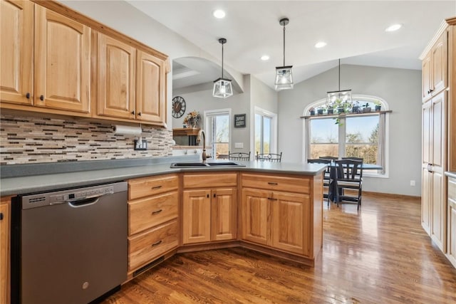 kitchen with a sink, backsplash, dark wood finished floors, a peninsula, and dishwasher