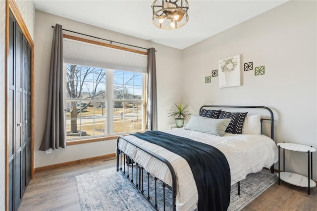 bedroom featuring a closet, baseboards, light wood-style floors, and a chandelier