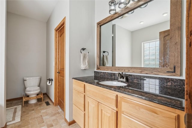 bathroom featuring toilet, vanity, and baseboards