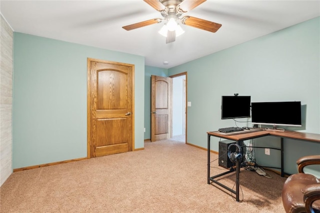 carpeted office space featuring ceiling fan and baseboards