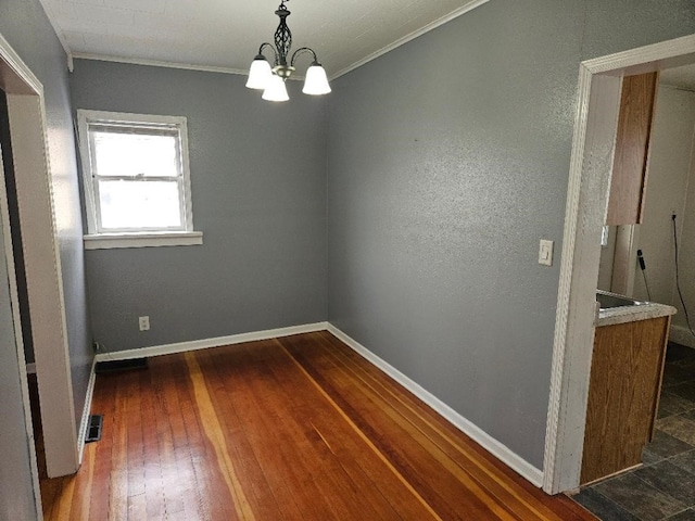 unfurnished room with visible vents, baseboards, a chandelier, ornamental molding, and dark wood-style floors