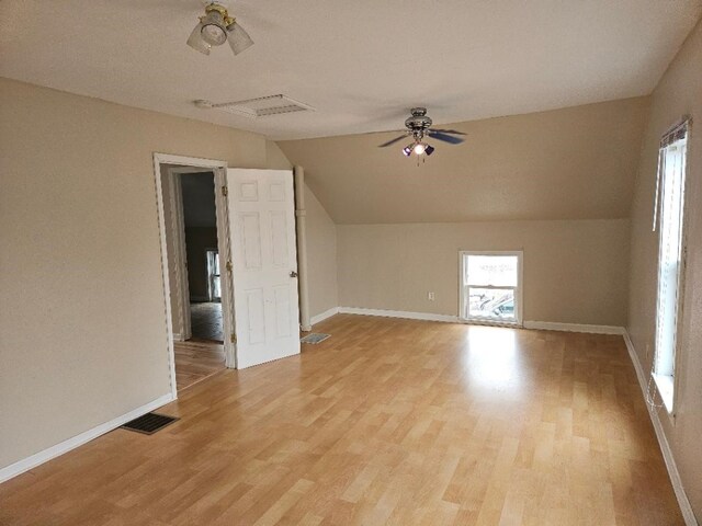 additional living space featuring visible vents, baseboards, light wood-style flooring, and vaulted ceiling