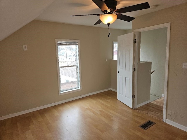 interior space featuring visible vents, baseboards, vaulted ceiling, and light wood finished floors