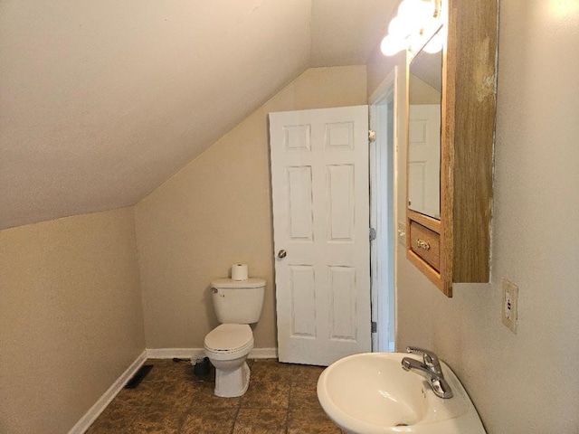 bathroom featuring toilet, lofted ceiling, baseboards, and a sink