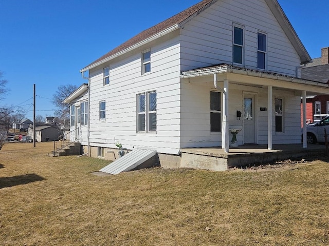 back of house featuring a yard, covered porch, and entry steps