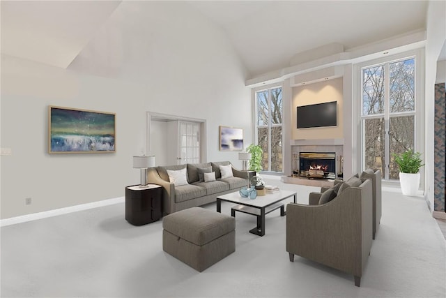 living room with plenty of natural light, baseboards, a warm lit fireplace, and high vaulted ceiling