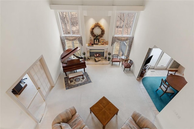 sitting room with carpet flooring, a glass covered fireplace, and a towering ceiling