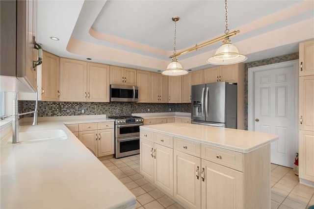 kitchen with light brown cabinets, light countertops, appliances with stainless steel finishes, a raised ceiling, and a center island