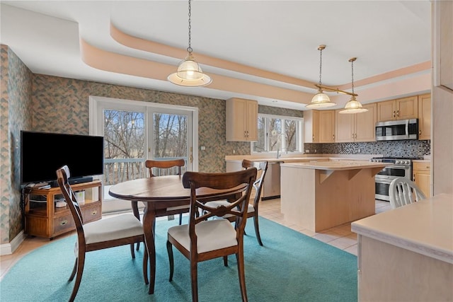 dining space with light tile patterned floors, wallpapered walls, and a raised ceiling