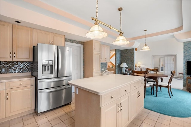 kitchen featuring a raised ceiling, light countertops, and stainless steel refrigerator with ice dispenser