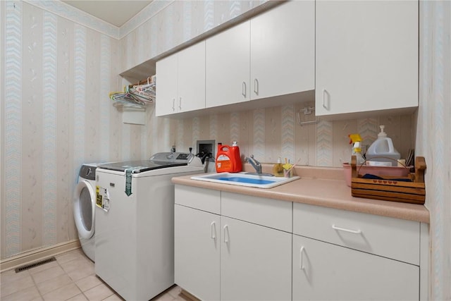 laundry area with visible vents, wallpapered walls, washer and clothes dryer, cabinet space, and a sink