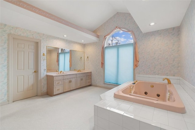 bathroom featuring a sink, a jetted tub, wallpapered walls, double vanity, and vaulted ceiling