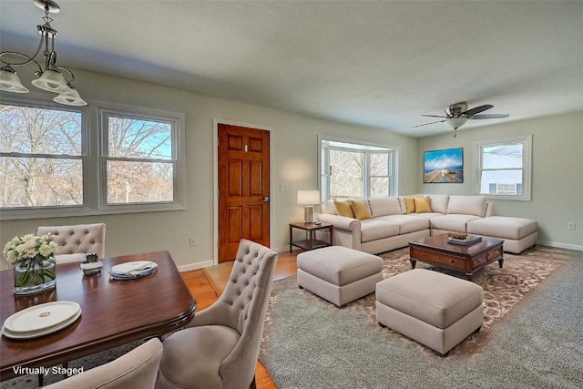 living area featuring baseboards, a healthy amount of sunlight, and a ceiling fan